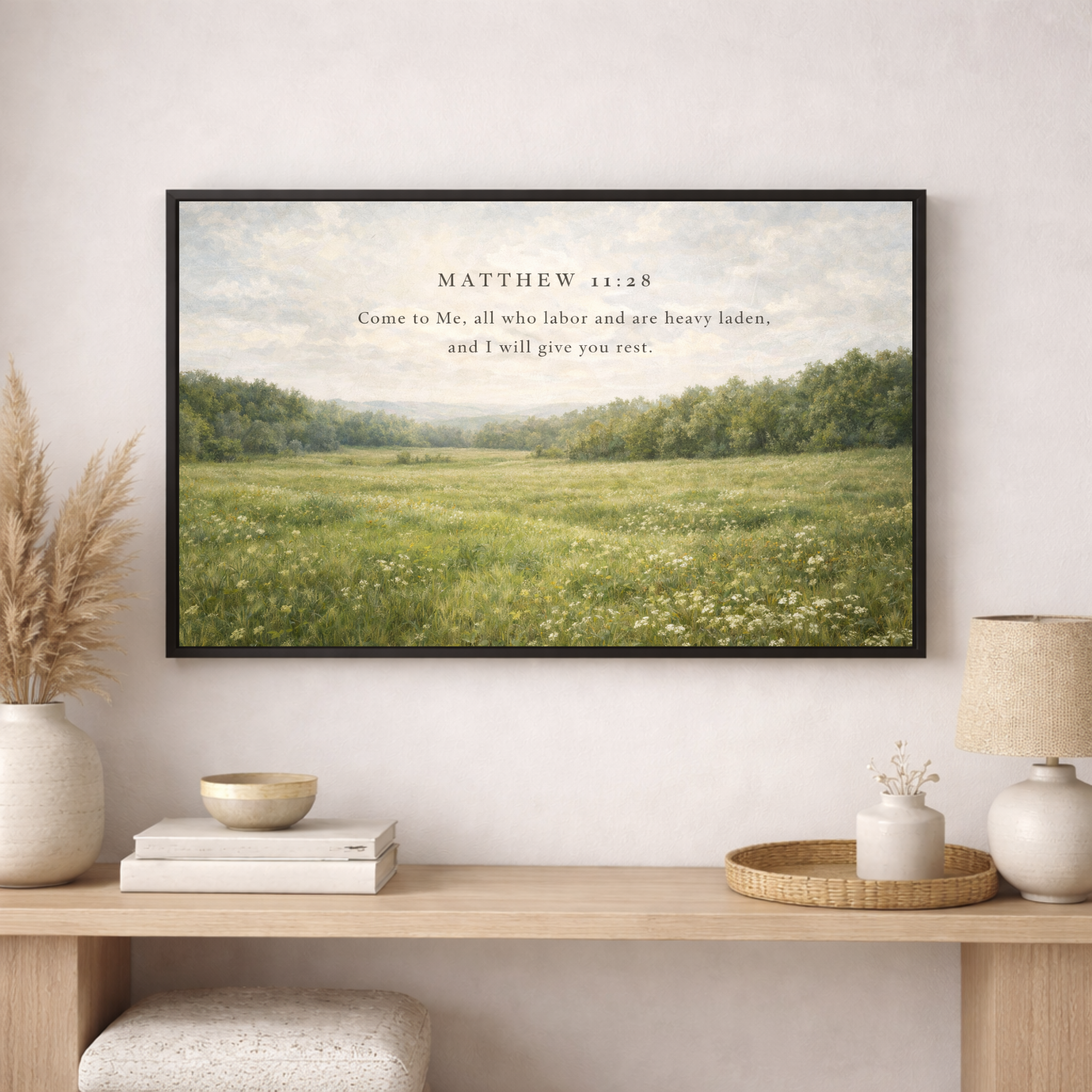 Framed artwork with a landscape scene and text on a wall above a wooden console table.