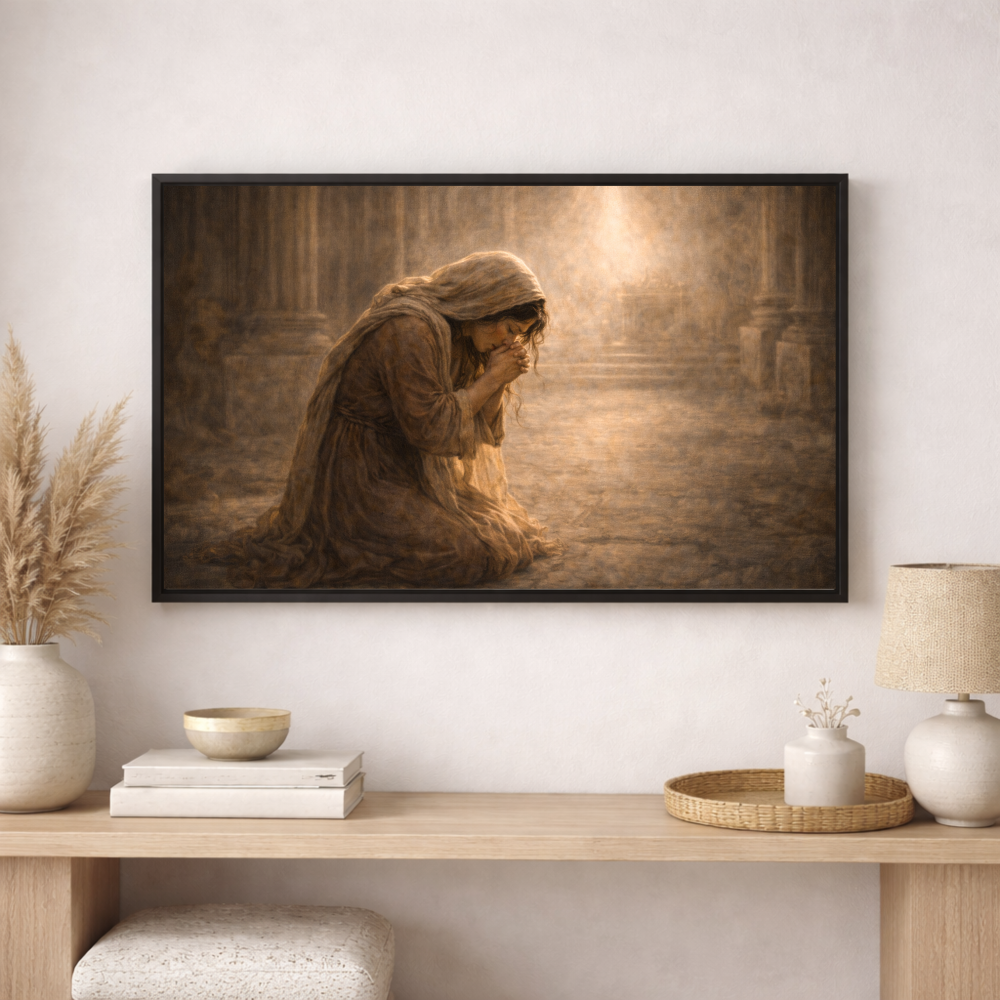 Framed artwork of a person in a hooded garment on a wall above a wooden console table with decorative items.