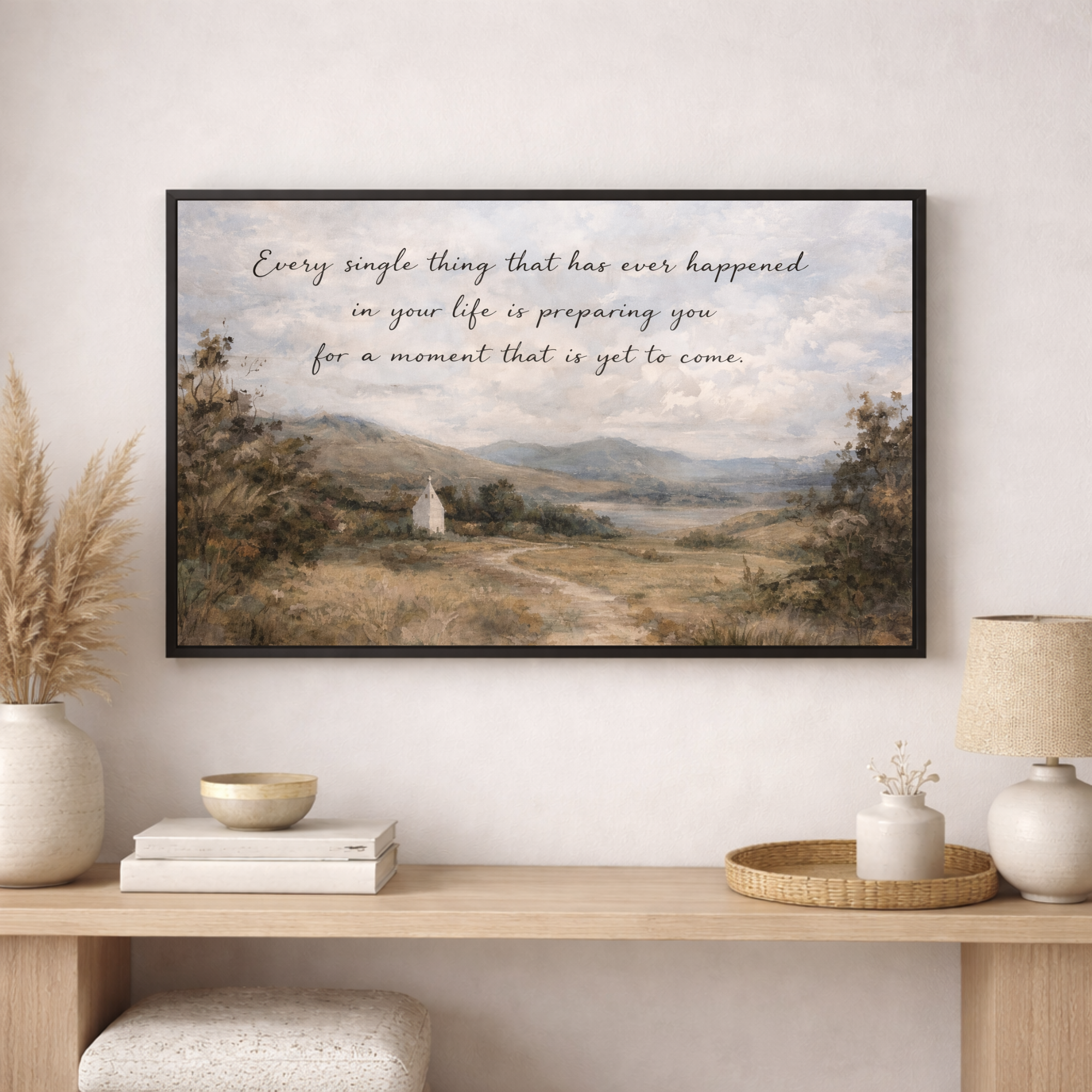 Framed landscape print with motivational quote on a wall above a wooden console table.