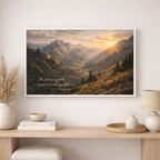 Framed mountain landscape print with scripture on a wall above a wooden console table.