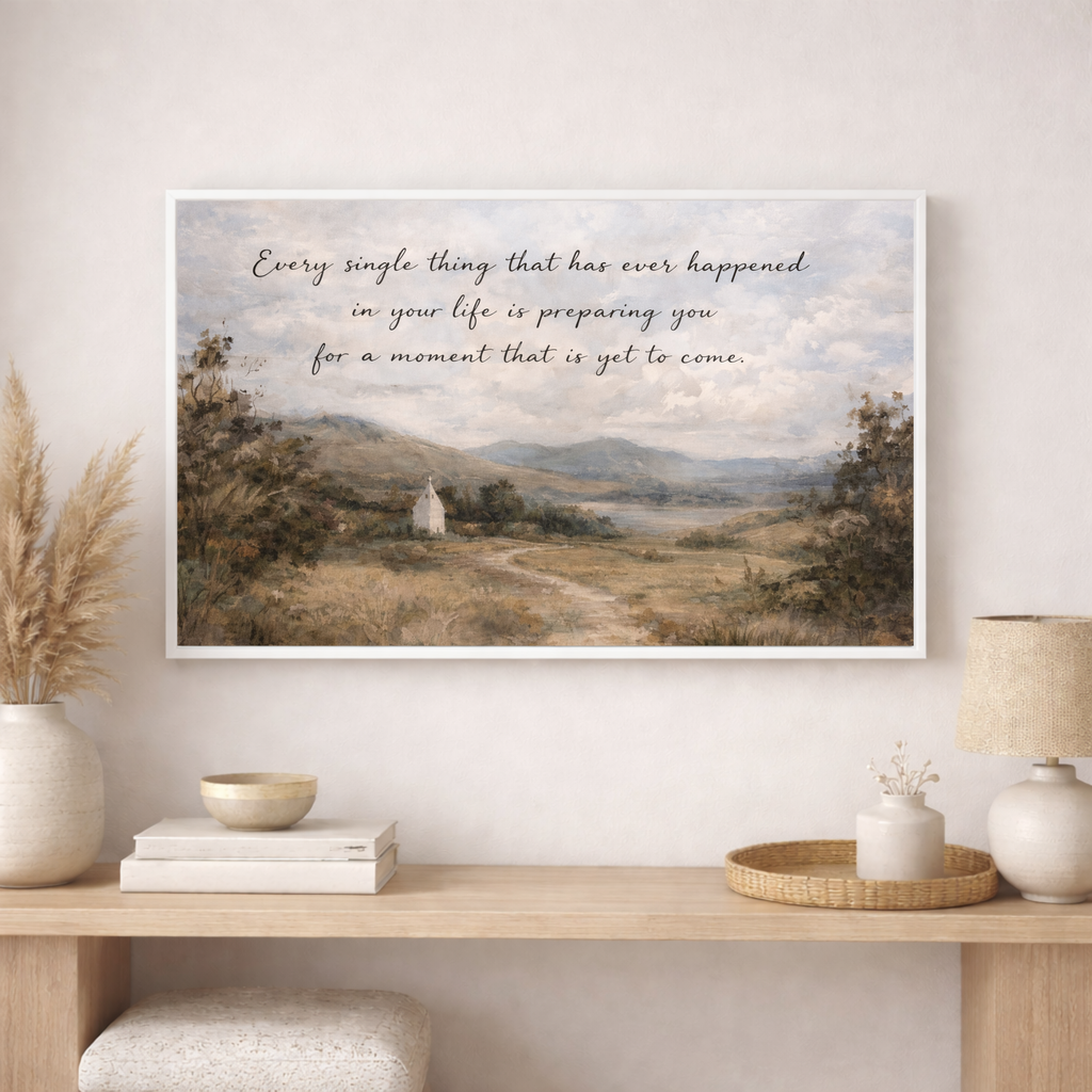 Framed artwork with a scenic landscape and motivational quote on a wall above a wooden console table.