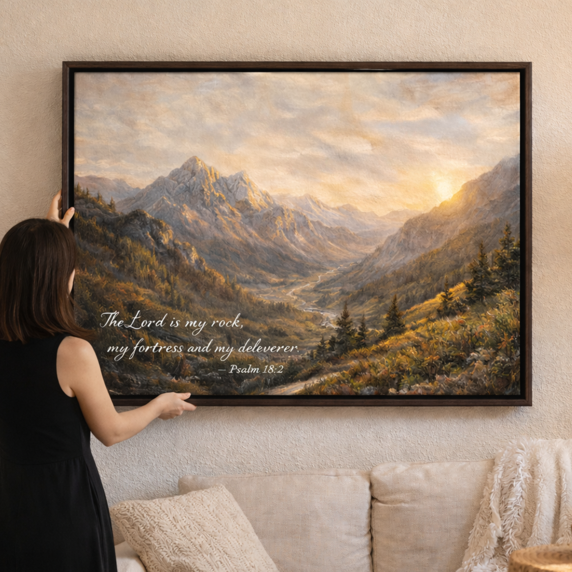 Woman hanging a framed landscape painting of mountains on a wall.